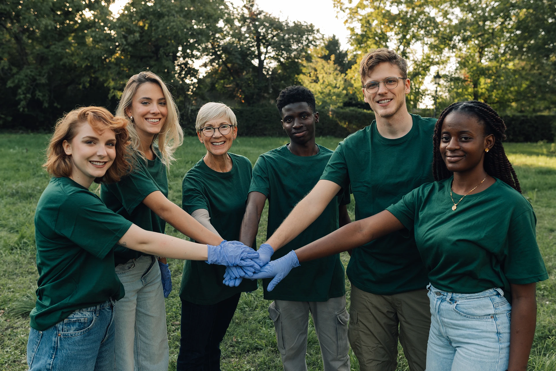 group-of-volunteers-putting-hands-together-wearing-green-shirt